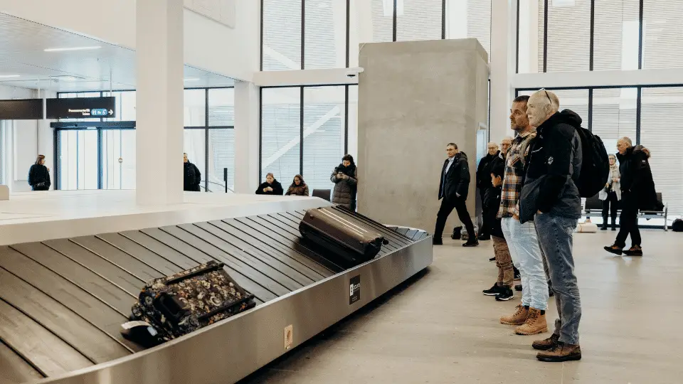 People waiting for luggage at an airport baggage carousel.